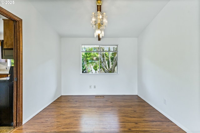 unfurnished dining area with baseboards, visible vents, wood finished floors, and a notable chandelier
