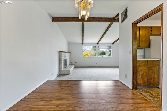 unfurnished living room featuring an inviting chandelier, a brick fireplace, baseboards, wood finished floors, and beamed ceiling