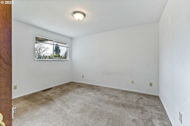 carpeted spare room with visible vents and baseboards