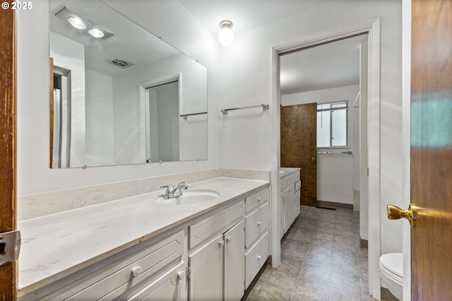 bathroom featuring toilet, visible vents, and vanity