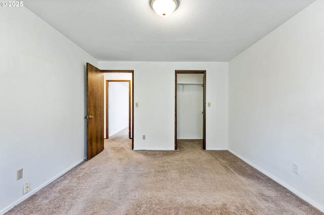 unfurnished bedroom featuring carpet floors, baseboards, a closet, and a textured ceiling