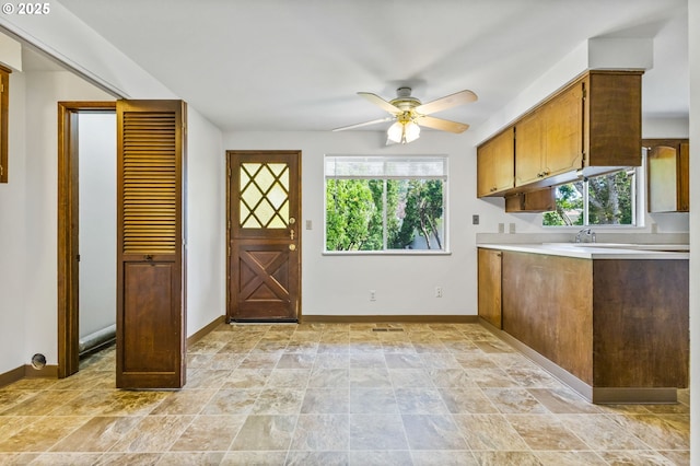 kitchen featuring light countertops, baseboards, ceiling fan, and a wealth of natural light