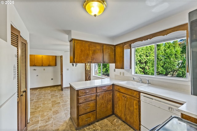 kitchen with light countertops, stone finish flooring, a peninsula, and dishwasher