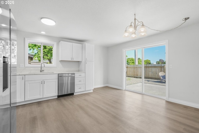 kitchen with stainless steel dishwasher, a sink, light wood-type flooring, and light countertops