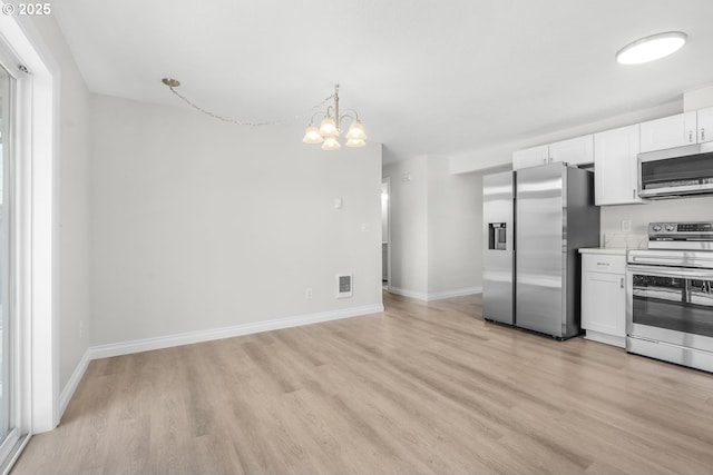 kitchen with appliances with stainless steel finishes, light wood-style floors, white cabinets, and a chandelier