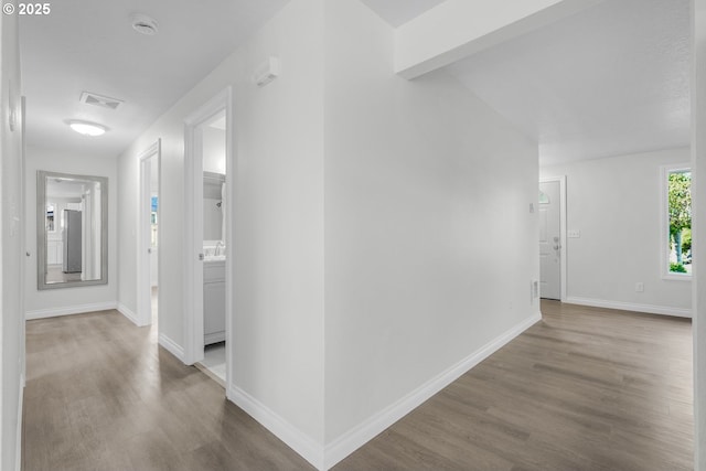 corridor featuring wood finished floors, baseboards, and a sink