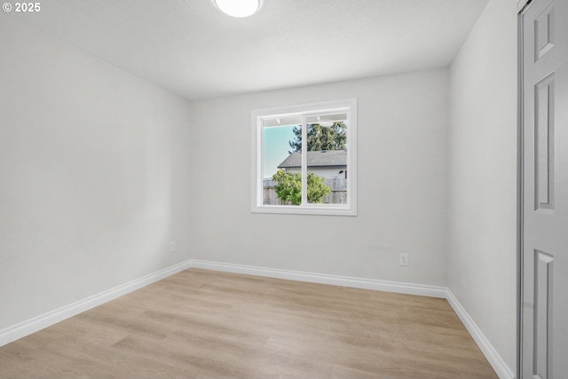 spare room featuring light wood-type flooring and baseboards