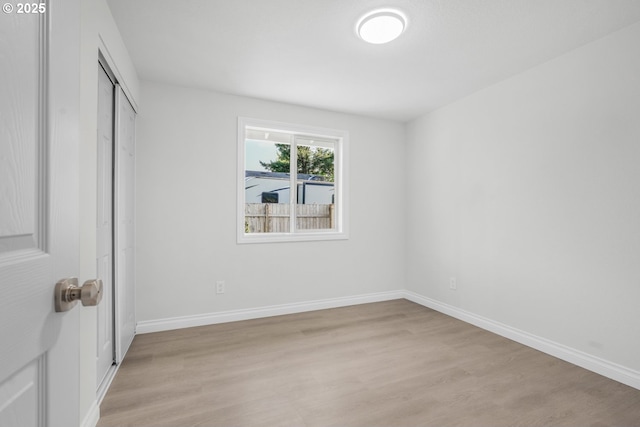 unfurnished bedroom featuring light wood-style floors, a closet, and baseboards