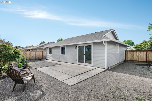 rear view of property featuring a fenced backyard, a patio area, and a shingled roof