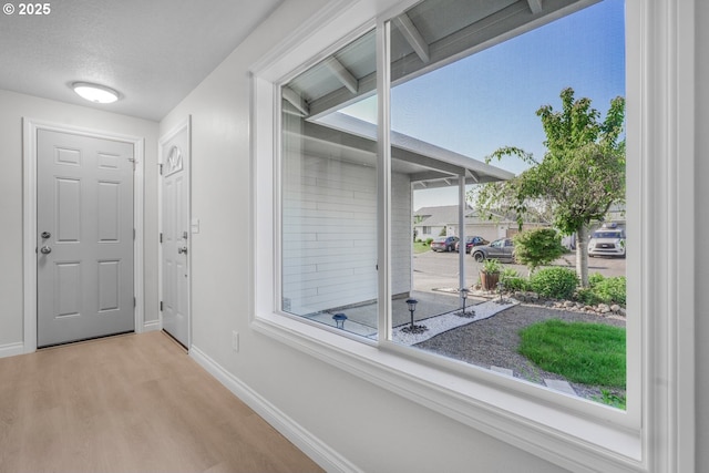 doorway to outside featuring wood finished floors, baseboards, and a textured ceiling