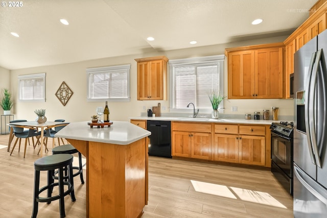 31070 NW Kaybern St, North Plains, OR 97133 - kitchen featuring black appliances, a center island, light countertops, light wood-type flooring, and a kitchen bar