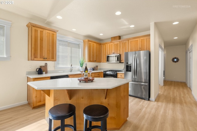 31070 NW Kaybern St, North Plains, OR 97133 - kitchen featuring black appliances, light wood-type flooring, light countertops, a breakfast bar area, and a center island