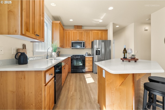 31070 NW Kaybern St, North Plains, OR 97133 - kitchen featuring black appliances, light wood-style flooring, a kitchen breakfast bar, a kitchen island, and light countertops