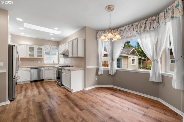 1670 NE Jackson School Rd, Hillsboro, OR 97124 - kitchen with appliances with stainless steel finishes, under cabinet range hood, light countertops, wood finished floors, and recessed lighting