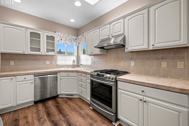 1670 NE Jackson School Rd, Hillsboro, OR 97124 - kitchen featuring stainless steel appliances, under cabinet range hood, a sink, glass insert cabinets, and white cabinets