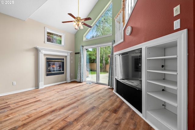 1670 NE Jackson School Rd, Hillsboro, OR 97124 - unfurnished living room with high vaulted ceiling, ceiling fan, wood finished floors, a glass covered fireplace, and baseboards