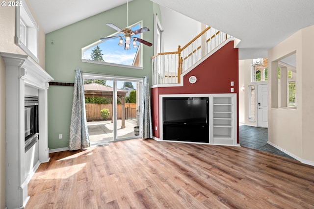 1670 NE Jackson School Rd, Hillsboro, OR 97124 - unfurnished living room with a ceiling fan, wood finished floors, a glass covered fireplace, baseboards, and a high ceiling