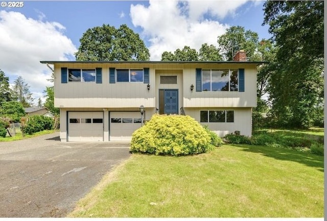 split foyer home with a front yard, driveway, a chimney, and an attached garage