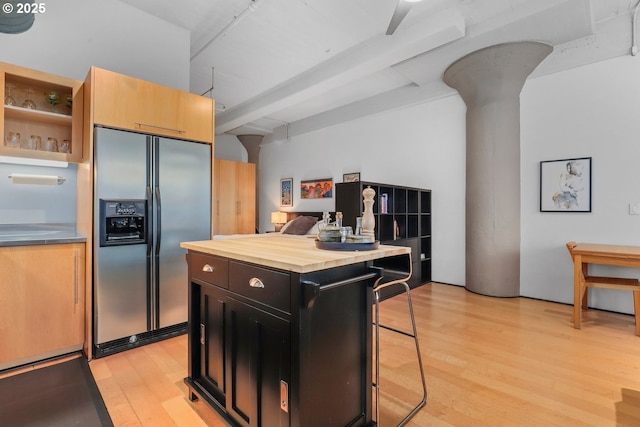 kitchen with a kitchen island, stainless steel refrigerator with ice dispenser, a kitchen bar, light hardwood / wood-style flooring, and wood counters