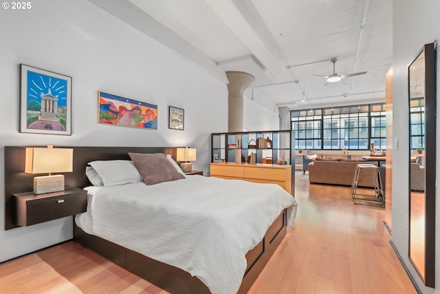 bedroom with ceiling fan, hardwood / wood-style floors, a wall of windows, and beam ceiling