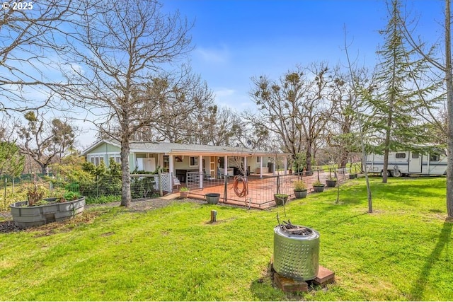 back of house featuring a patio, a yard, fence, and a vegetable garden