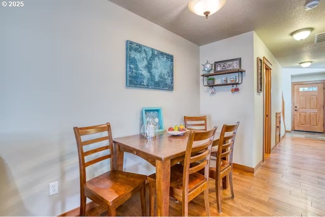 dining room featuring a textured ceiling and light hardwood / wood-style floors