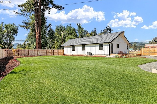 rear view of house featuring a lawn and central AC