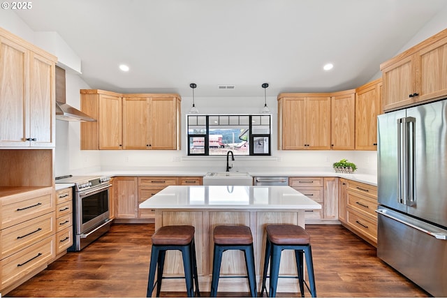 kitchen with appliances with stainless steel finishes, a center island, decorative light fixtures, sink, and a breakfast bar area