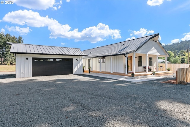 modern farmhouse style home featuring a porch, a garage, and an outbuilding