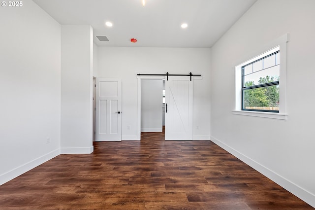 empty room featuring a barn door and dark hardwood / wood-style flooring