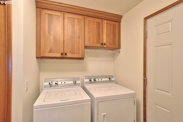 clothes washing area featuring washer and clothes dryer and cabinets