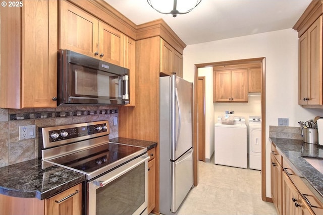 kitchen with backsplash, dark stone countertops, washer and clothes dryer, and appliances with stainless steel finishes