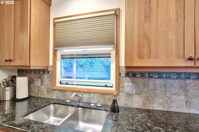 kitchen with backsplash, dark stone countertops, and sink