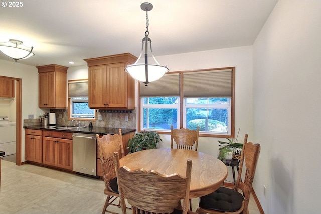 kitchen with dishwasher, sink, tasteful backsplash, washer / clothes dryer, and decorative light fixtures