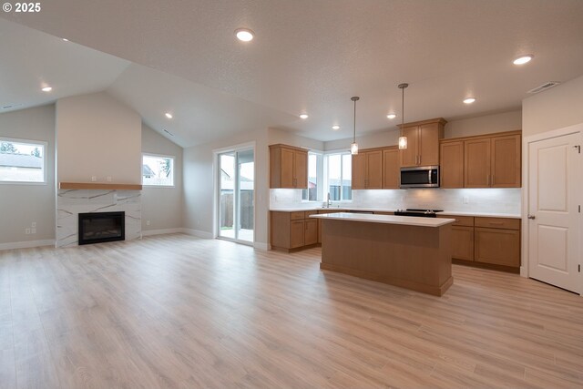 kitchen with stainless steel appliances, a center island, lofted ceiling, light hardwood / wood-style floors, and hanging light fixtures