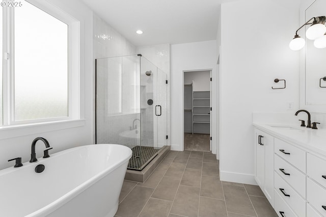 full bathroom with a walk in closet, a soaking tub, a stall shower, vanity, and tile patterned flooring