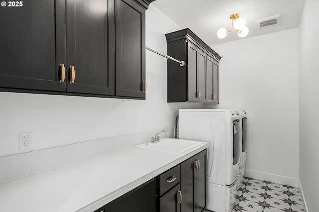 laundry area featuring light floors, visible vents, cabinet space, a sink, and washer and clothes dryer