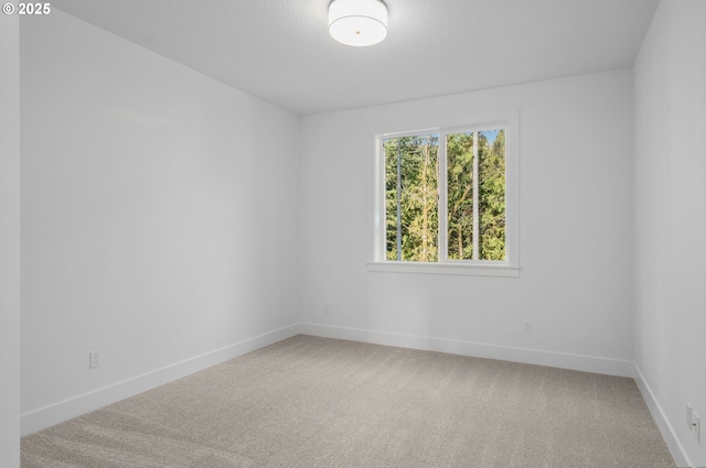 spare room featuring light colored carpet and baseboards