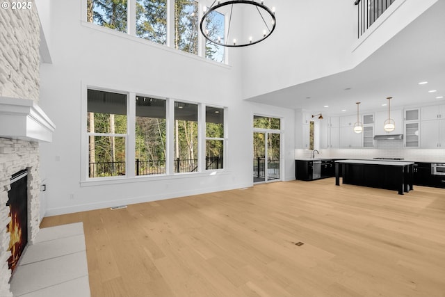 living room with baseboards, visible vents, light wood-style floors, a fireplace, and a chandelier