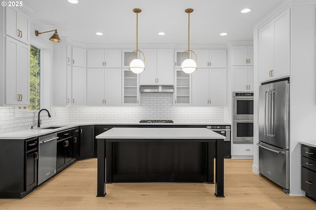 kitchen with under cabinet range hood, appliances with stainless steel finishes, white cabinets, and a sink