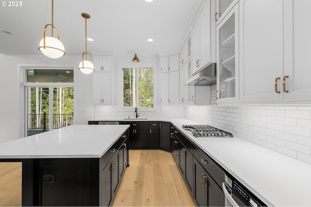 kitchen with under cabinet range hood, a sink, white cabinets, dark cabinetry, and stainless steel gas stovetop