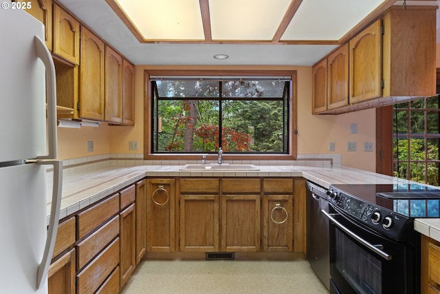 1705 SW 24th Dr, Gresham, OR 97080 - kitchen with freestanding refrigerator, black / electric stove, a sink, dishwasher, and plenty of natural light