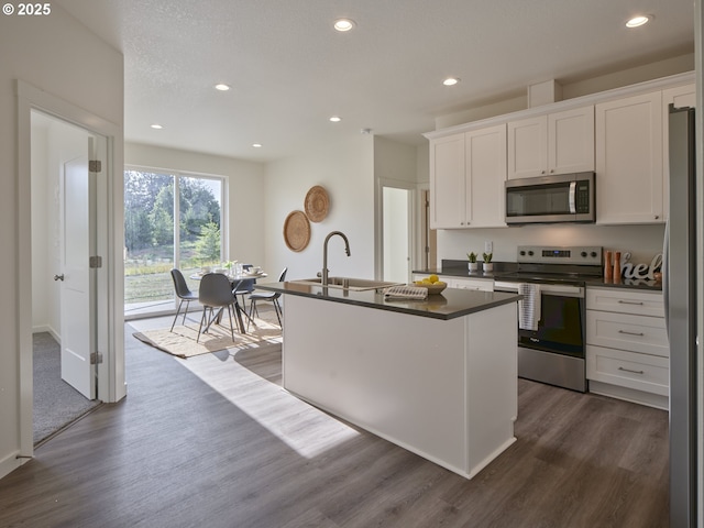 521 Kakela Rd, Winlock, WA 98596 - kitchen featuring stainless steel appliances, a sink, dark countertops, white cabinets, and a kitchen island with sink