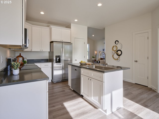 521 Kakela Rd, Winlock, WA 98596 - kitchen with appliances with stainless steel finishes, dark countertops, a sink, a kitchen island with sink, and white cabinetry