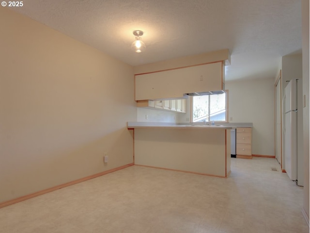 9435 SW 53rd Ave, Portland, OR 97219 - kitchen with a peninsula, light flooring, baseboards, and light countertops