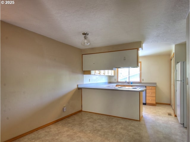 9435 SW 53rd Ave, Portland, OR 97219 - kitchen with freestanding refrigerator, a peninsula, baseboards, a textured ceiling, and light countertops