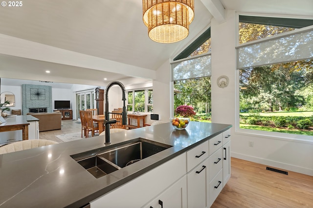 kitchen with dark countertops, a sink, baseboards, open floor plan, and vaulted ceiling with beams