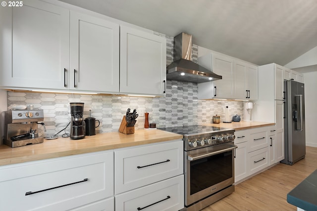 kitchen featuring appliances with stainless steel finishes, light wood-style flooring, wall chimney exhaust hood, tasteful backsplash, and butcher block counters