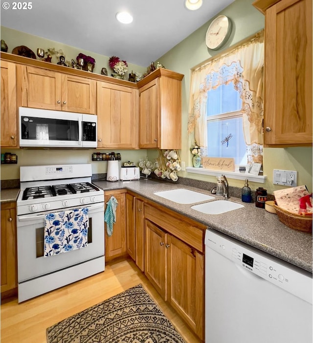 kitchen with white appliances, a sink, light wood-style floors, and recessed lighting