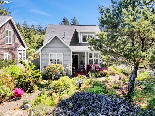 rear view of property featuring a deck, fence, and a shingled roof